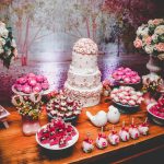 A beautifully arranged dessert table featuring a tiered cake, sweets, and floral arrangements.